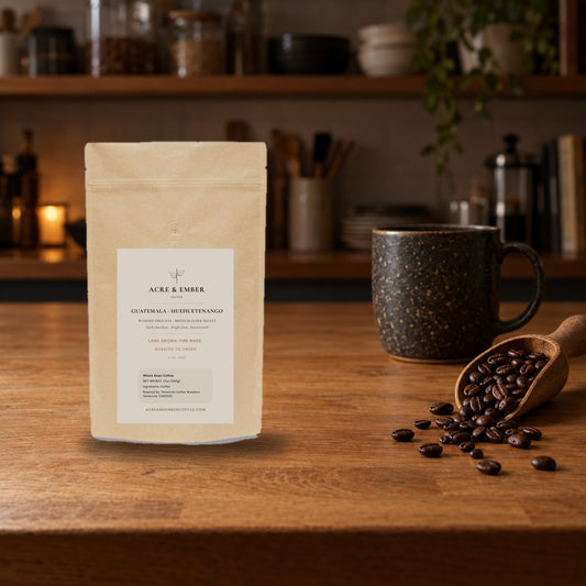 Acre & Ember Guatemala Huehuetenango washed whole bean coffee bag on a warm kitchen counter with a scoop of roasted beans